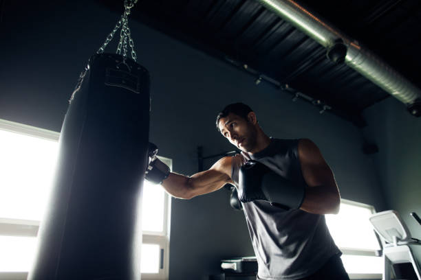 concentrated young man box training by himself in the gym.